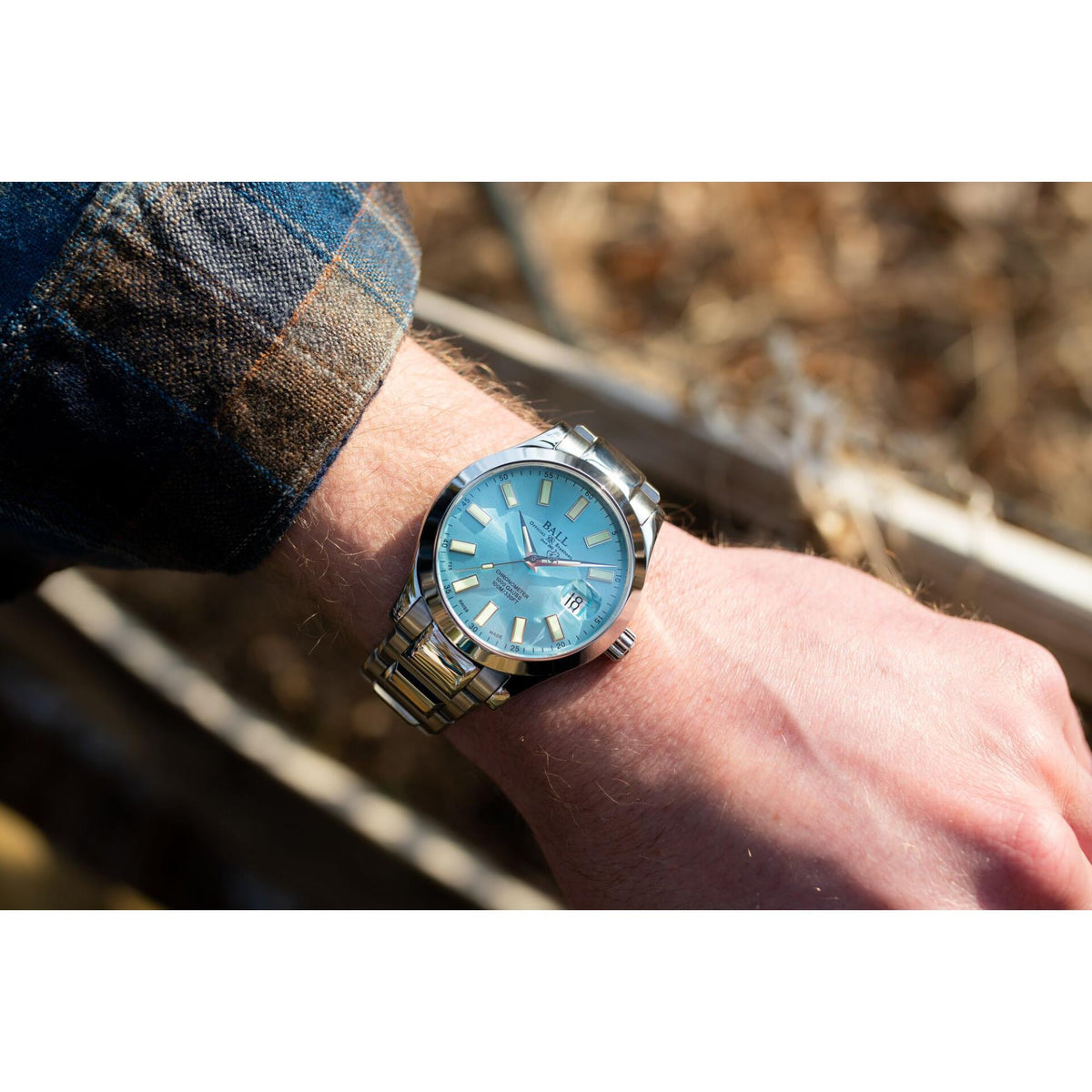 Stainless steel men’s watch with ice blue dial on wrist, metal bracelet and bezel visible