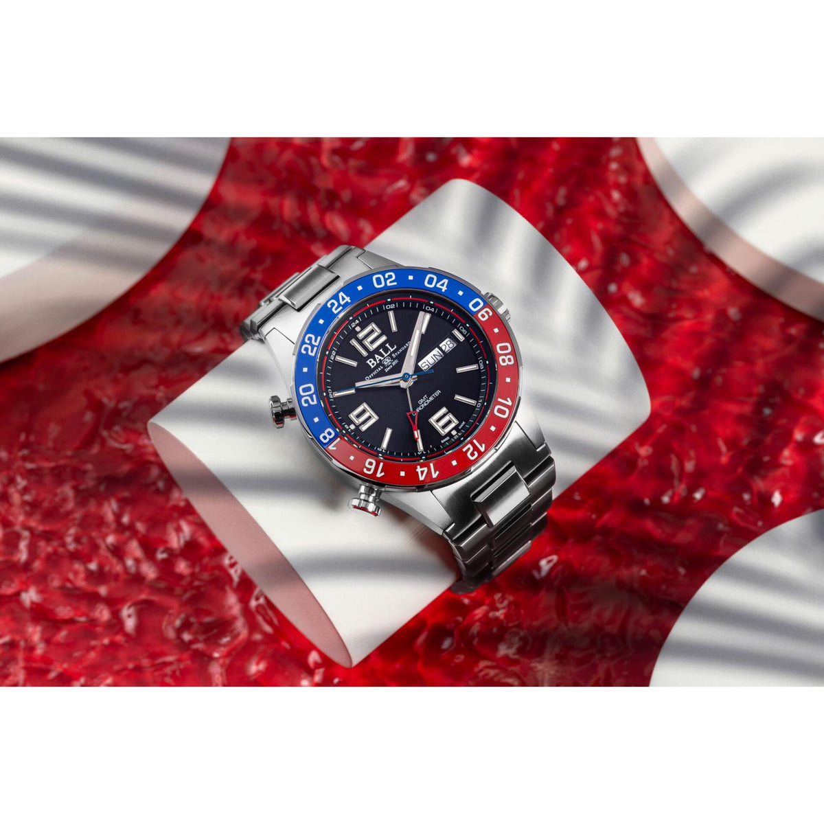 Men's steel diver wristwatch with black dial, blue/red bezel, and metal bracelet