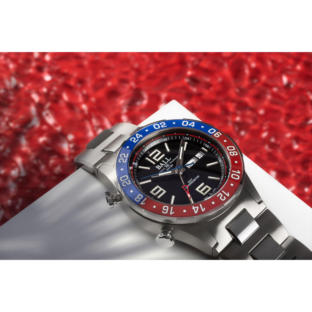 Men's steel diver wristwatch, black dial with blue/red bezel, angled close view