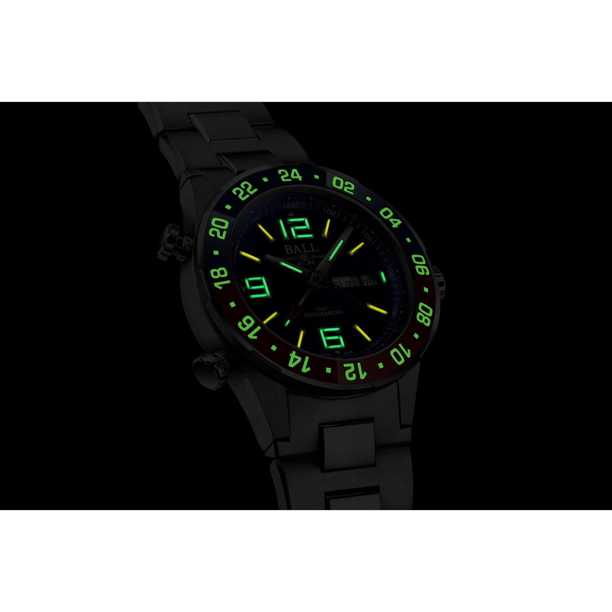 Close-up of men's black steel wristwatch dial with green luminous hour markers