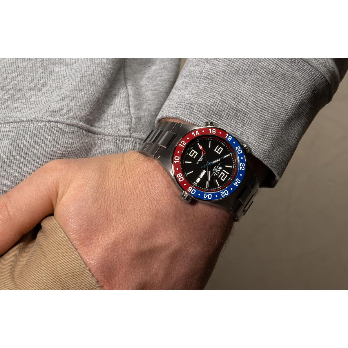 Men's titanium wristwatch with black dial and red/blue bezel, on wrist