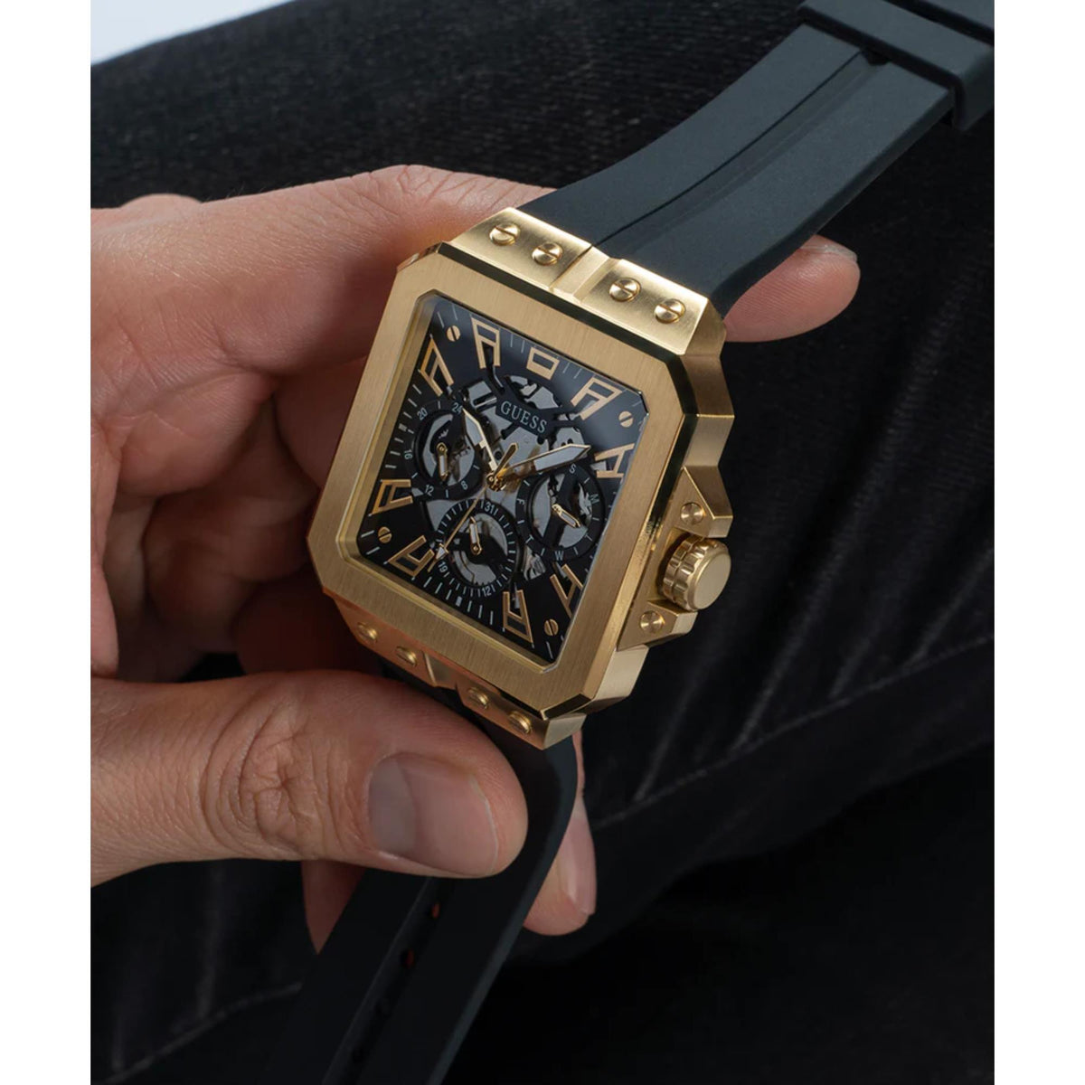 Men's Guess Leo watch close-up on wrist, gold-tone case, black dial, black silicone band