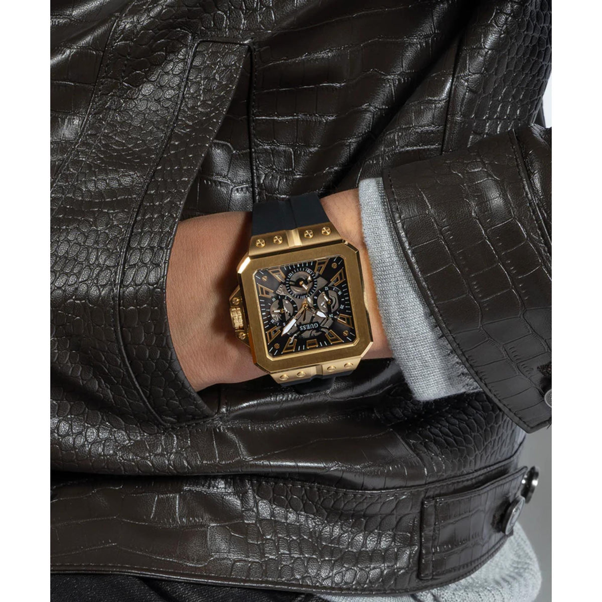 Men's Guess Leo watch on wrist, black dial and gold-tone octagonal case with black strap
