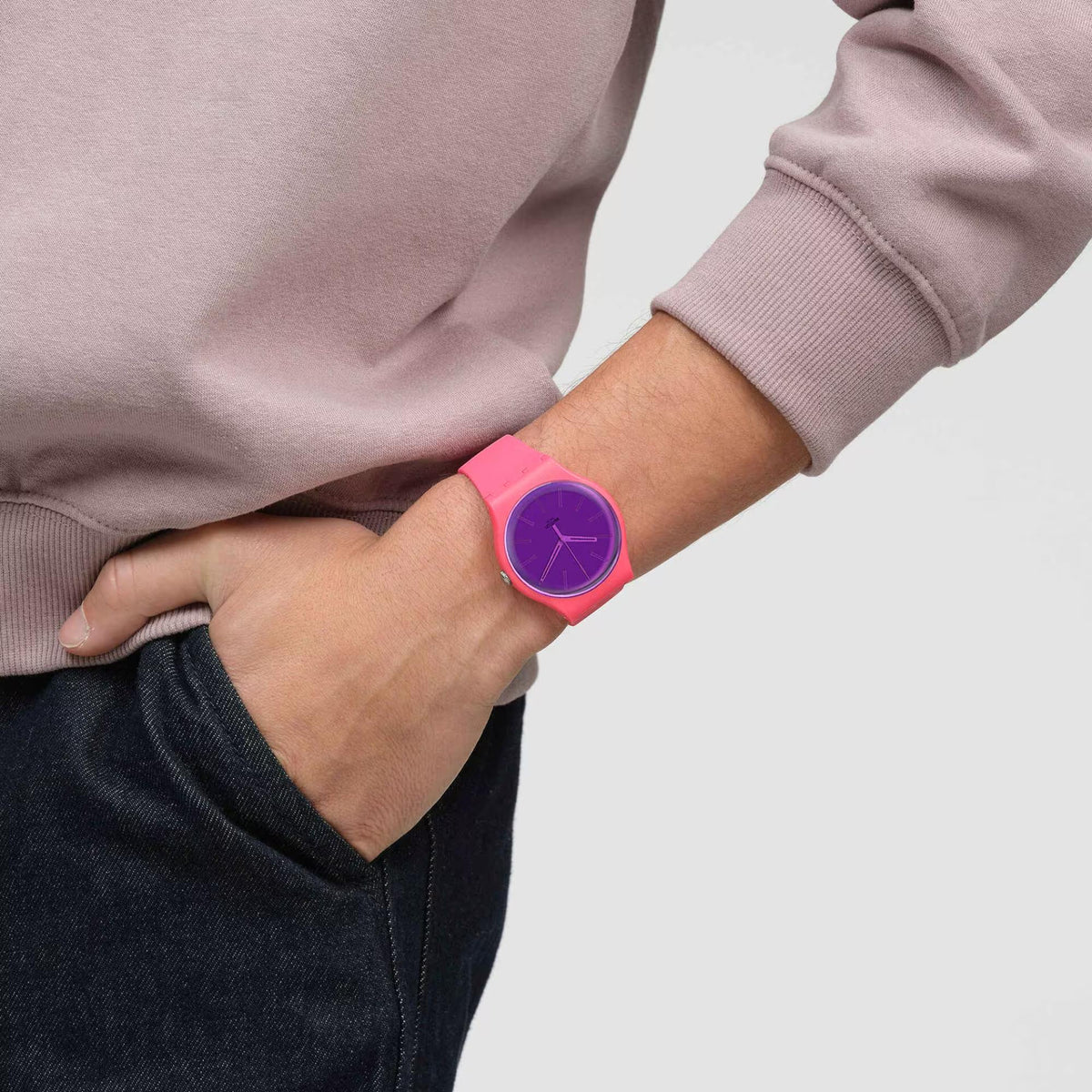 Swatch pink silicone watch on wrist with purple dial and slim hands