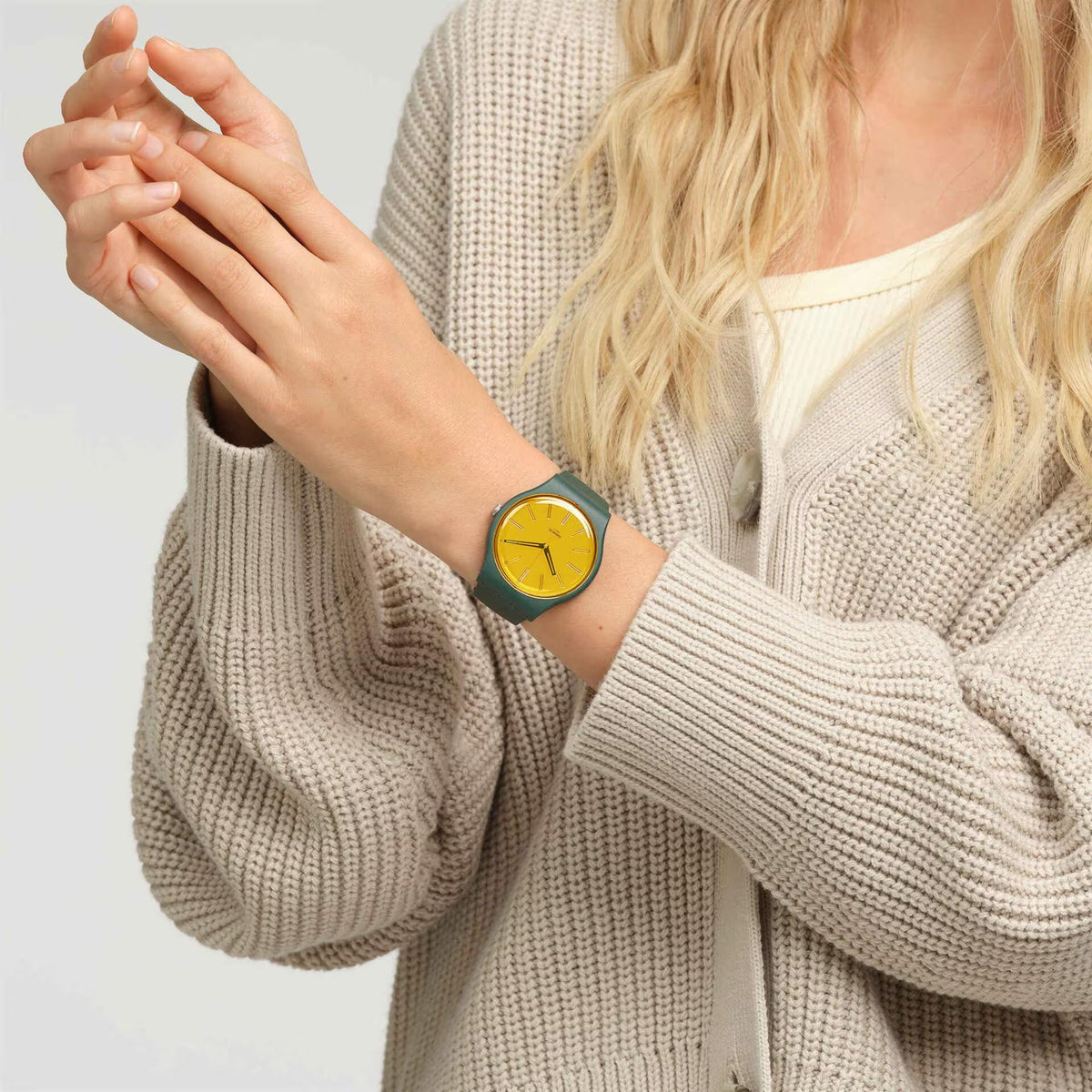 Swatch analog watch on wrist, yellow dial and dark green silicone strap