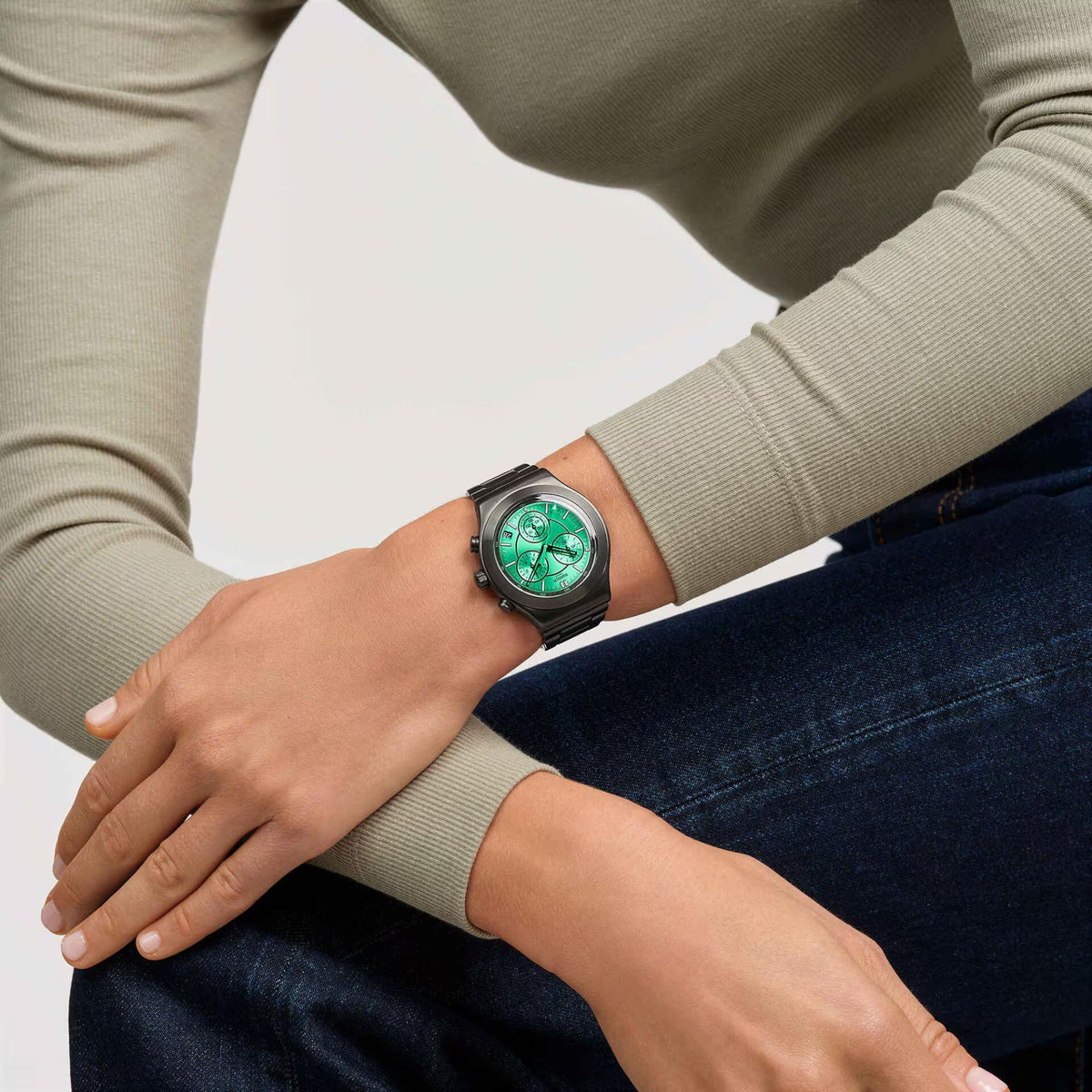 Swatch wristwatch with dark steel bracelet and bright green dial on a wearer’s arm