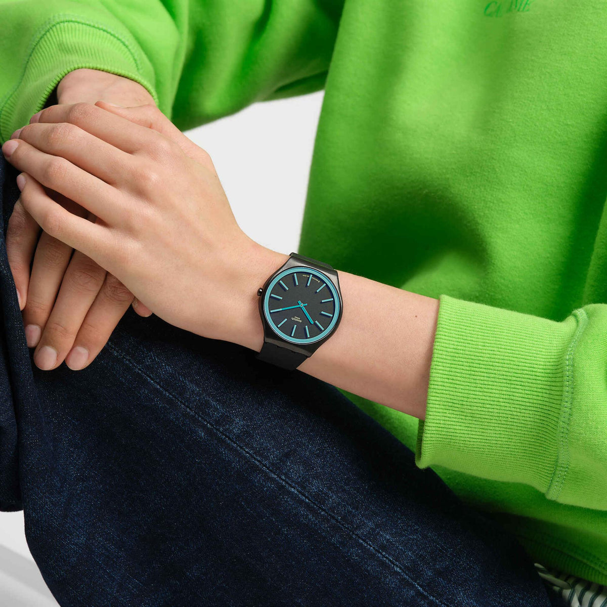Black silicone strap watch on wrist with blue dial and turquoise hands