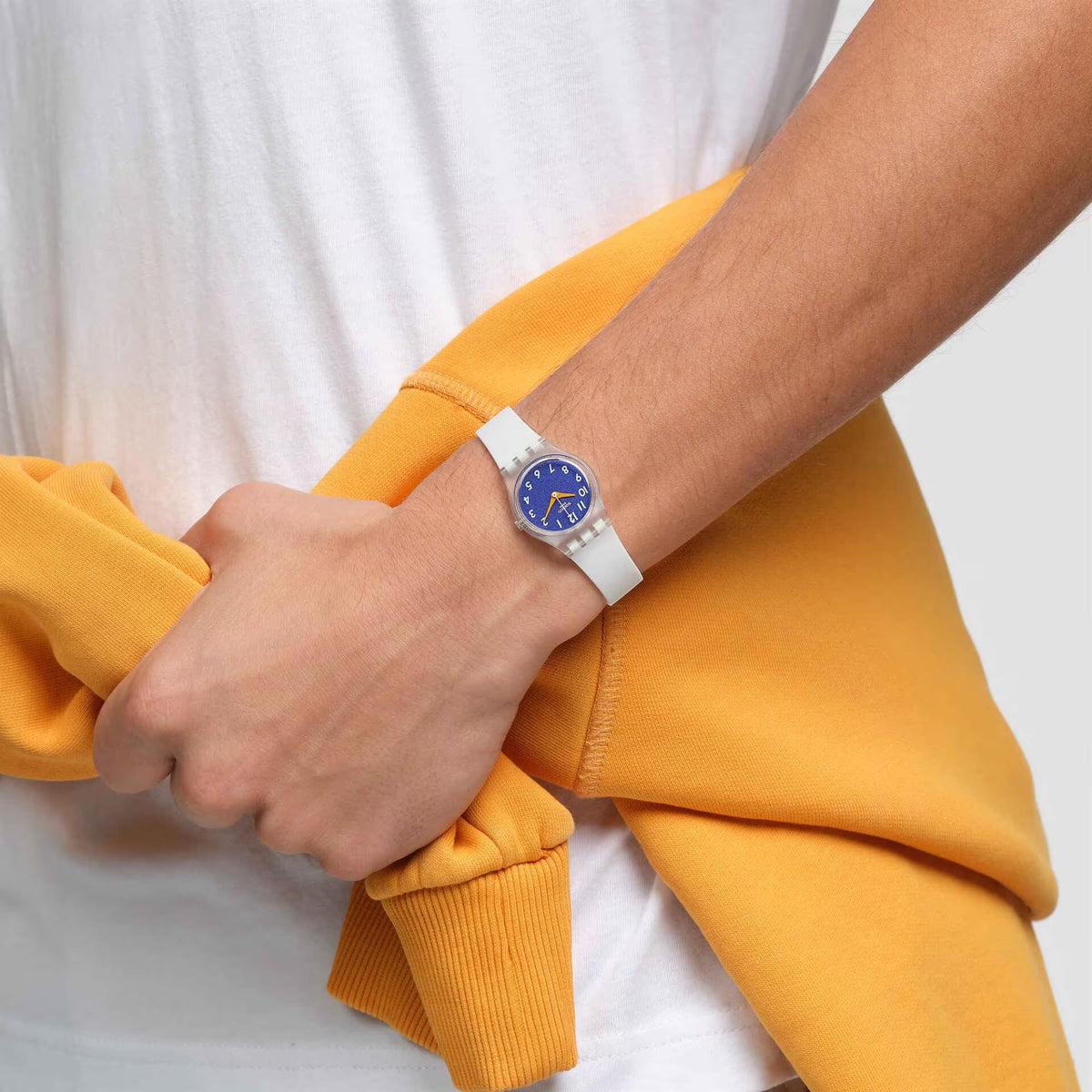 Blue dial Swatch watch on white silicone strap, worn on wrist with silver case