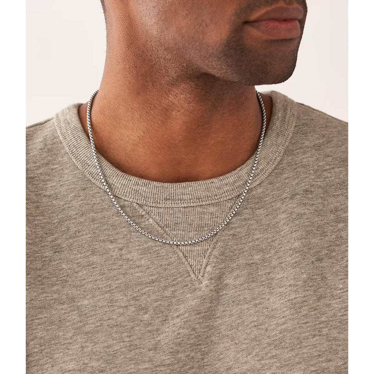 Stainless steel chain necklace on crewneck shirt, silver-toned links and center drop