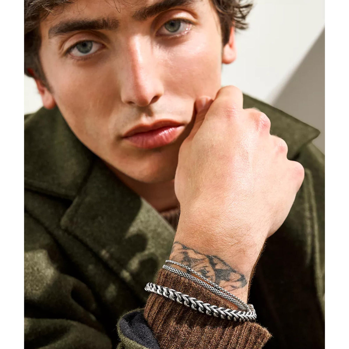 Men's silver mesh chain bracelet on wrist, close-up of woven texture and clasp