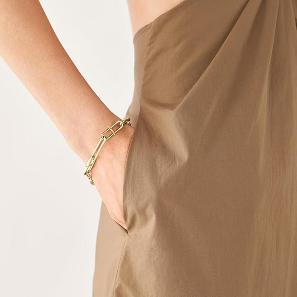 Gold-tone chain link bracelet on wrist with rectangular clasp and hinged links