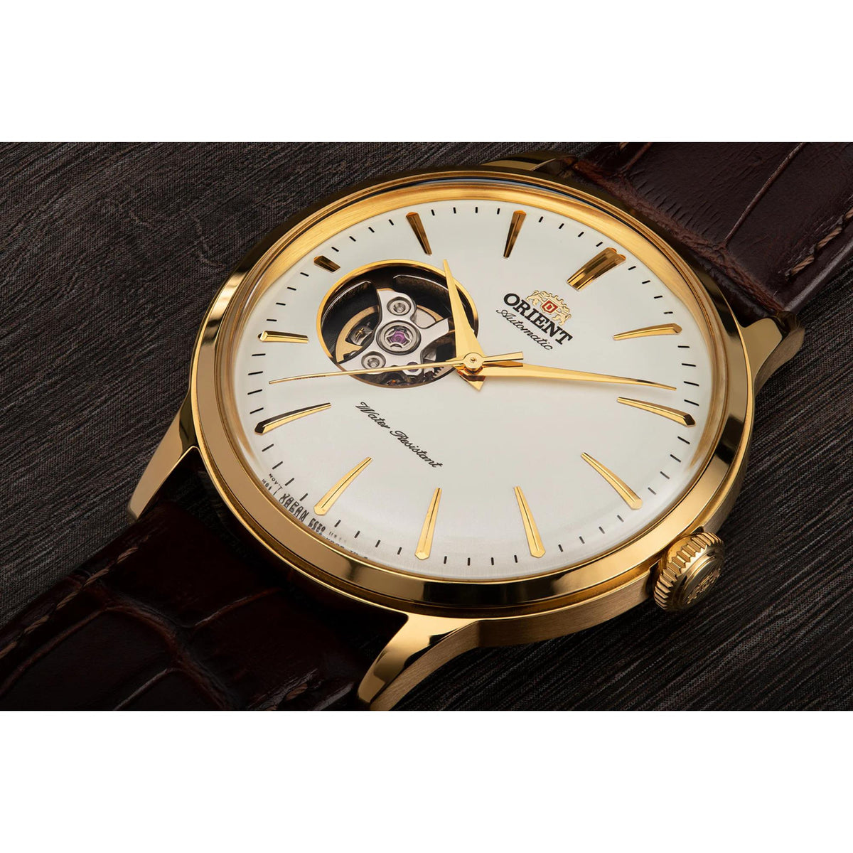 Gold-tone automatic watch close-up with white open-heart dial and brown leather strap