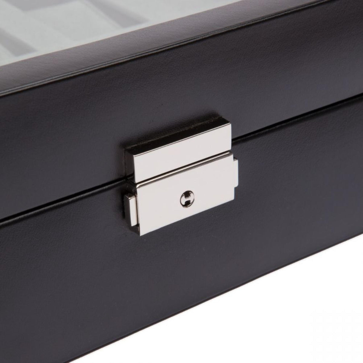 Metal clasp on black watch box lid with round keyhole detail.