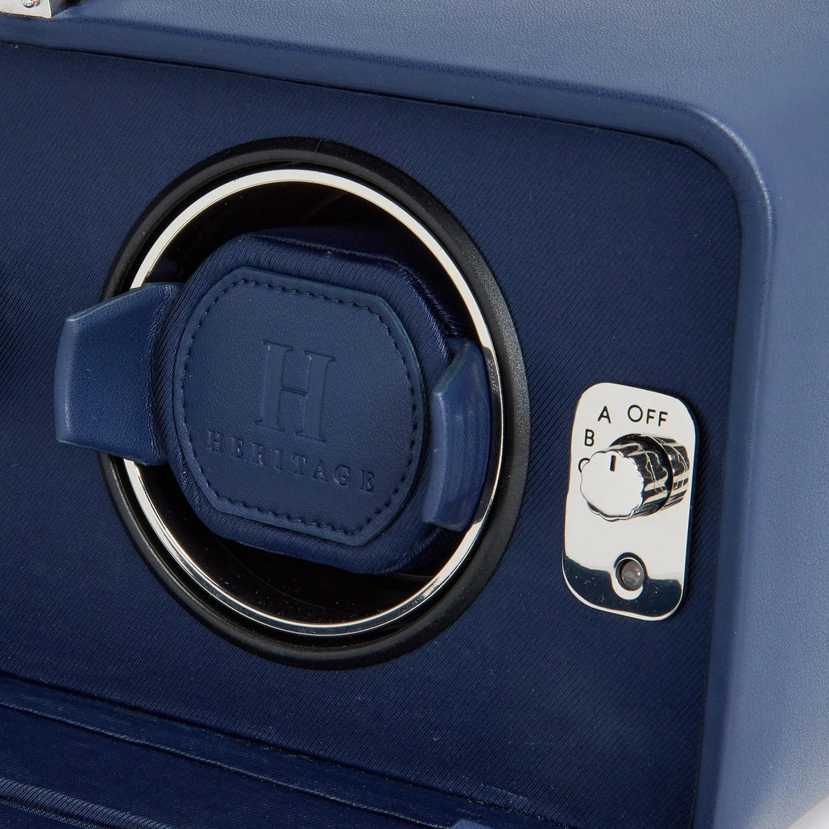 Close-up of a blue watch winder with 'Heritage' branding on a matching blue background.