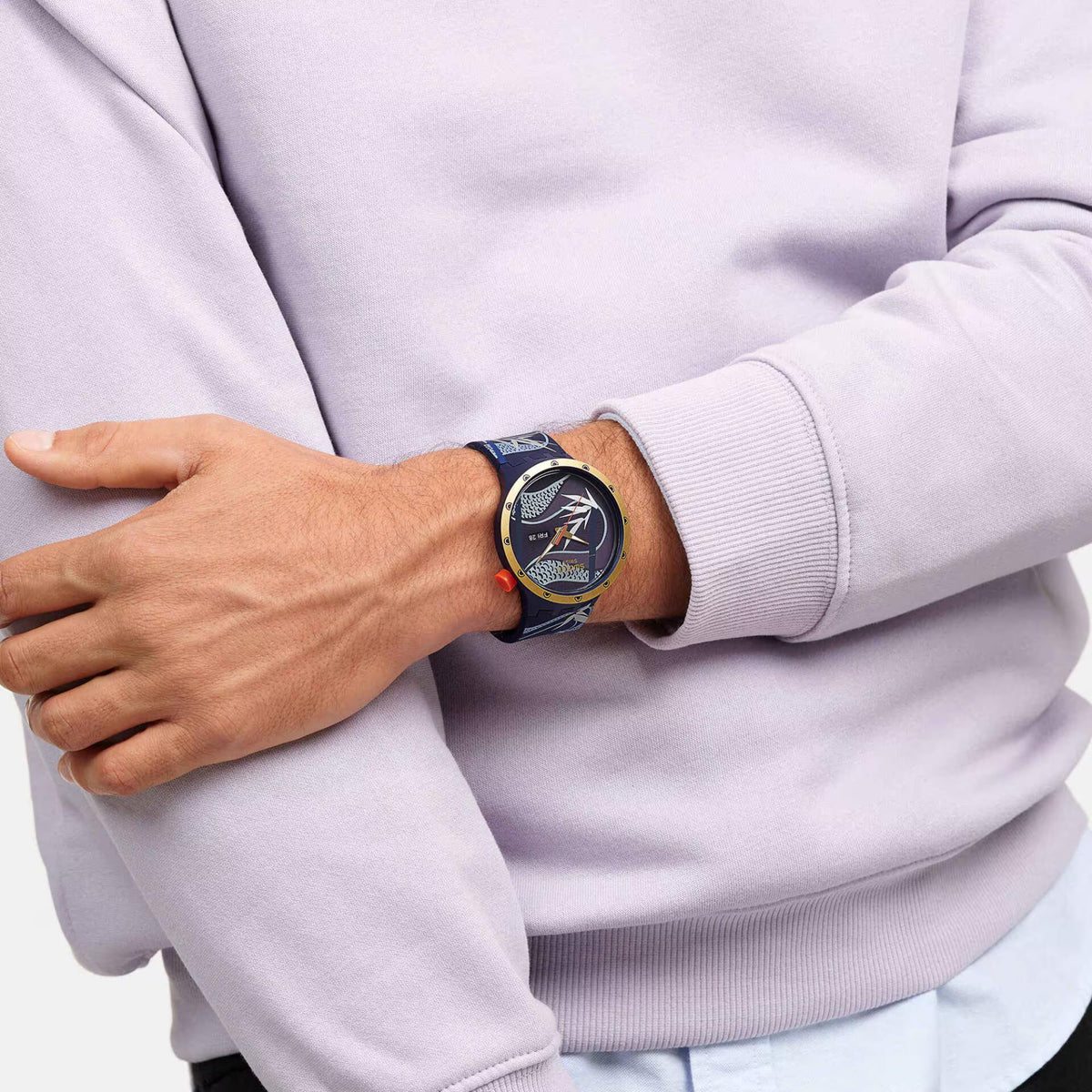 Men's blue silicone strap watch on wrist, dark patterned dial with gold hands