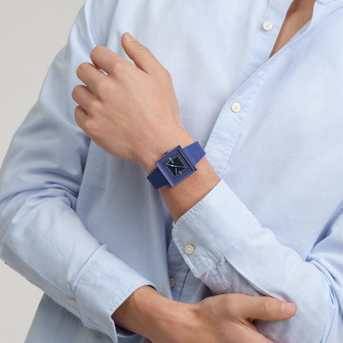 Dark blue square watch on wrist with silicone band and analog dial showing THU 28