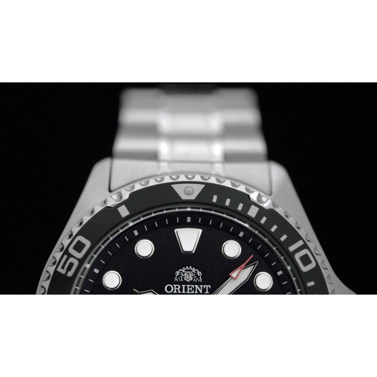 Close-up of black dial with silver markers, bezel numbers, and “ORIENT”