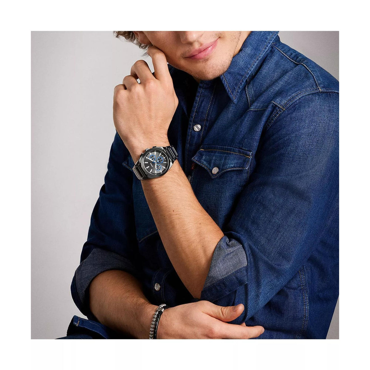 Model wearing the Fossil Everett FS6107 chronograph watch with a denim shirt, displaying the gunmetal case and grey dial