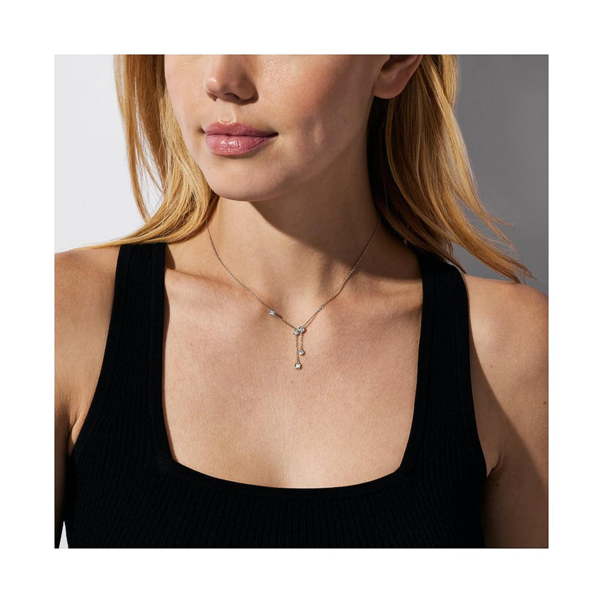 Sterling silver pendant necklace with three small crystal-set charms on model