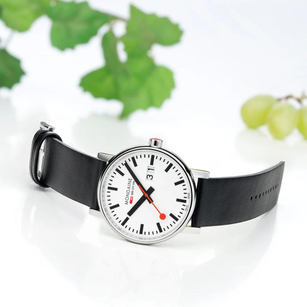 Mondaine Evo2 MSE.40210.LBV Swiss Railways timepiece displayed on a white surface next to green grapes