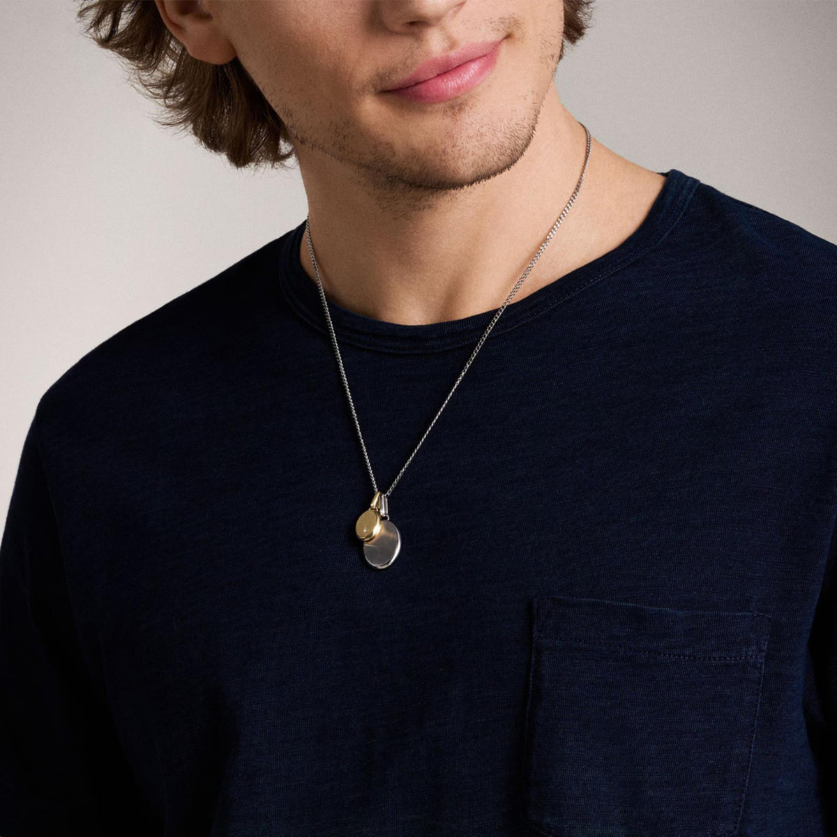 Two-tone stainless steel pendant necklace with oval gold and silver pendants, on chain.