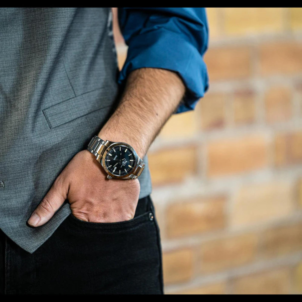 Men's wrist watch on arm, silver case and bracelet with black dial