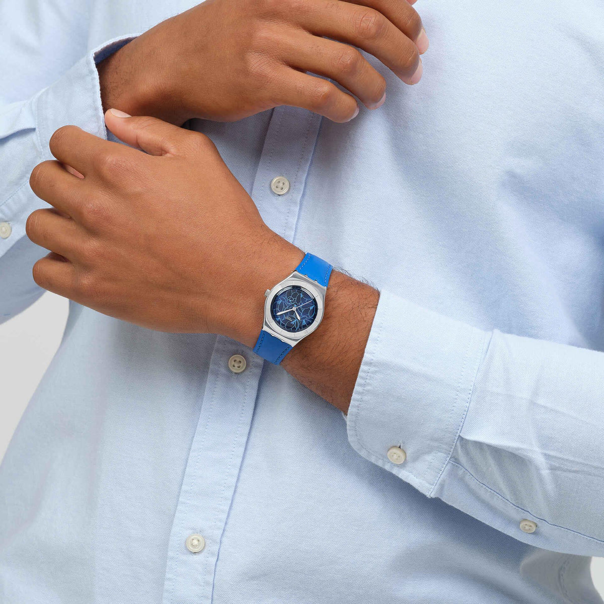 Man wearing blue leather strap watch, blue floral dial visible on silver case