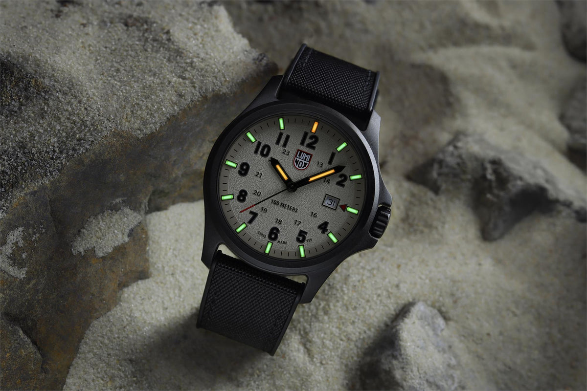 Black field watch with grey dial, luminous markers, and textured fabric strap