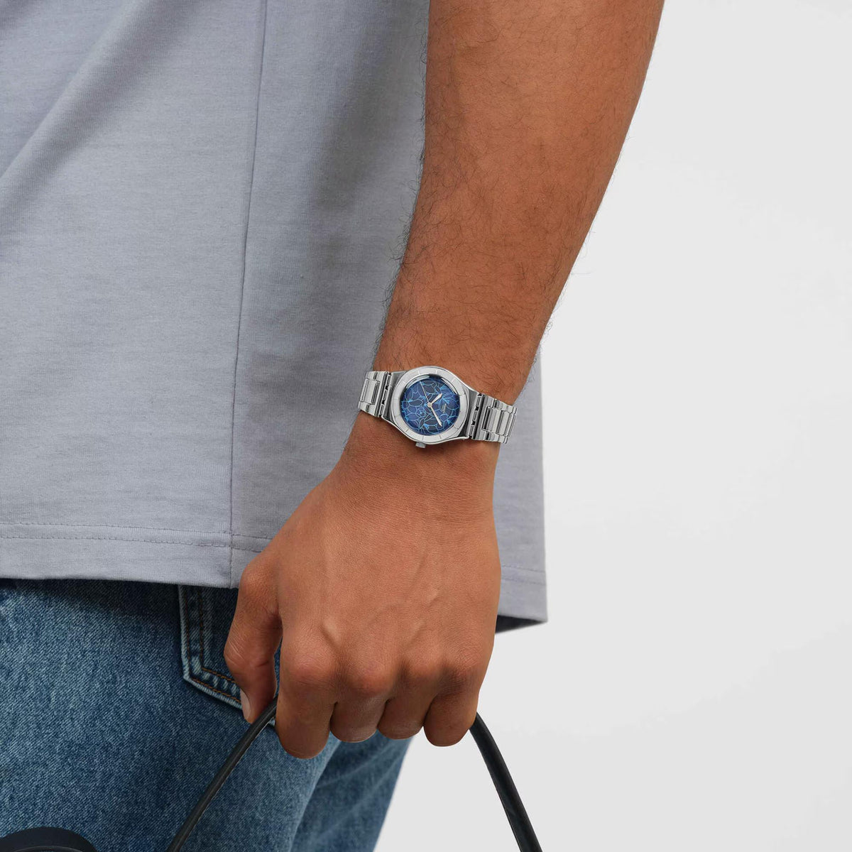 Steel strap wristwatch with blue floral dial on a hand