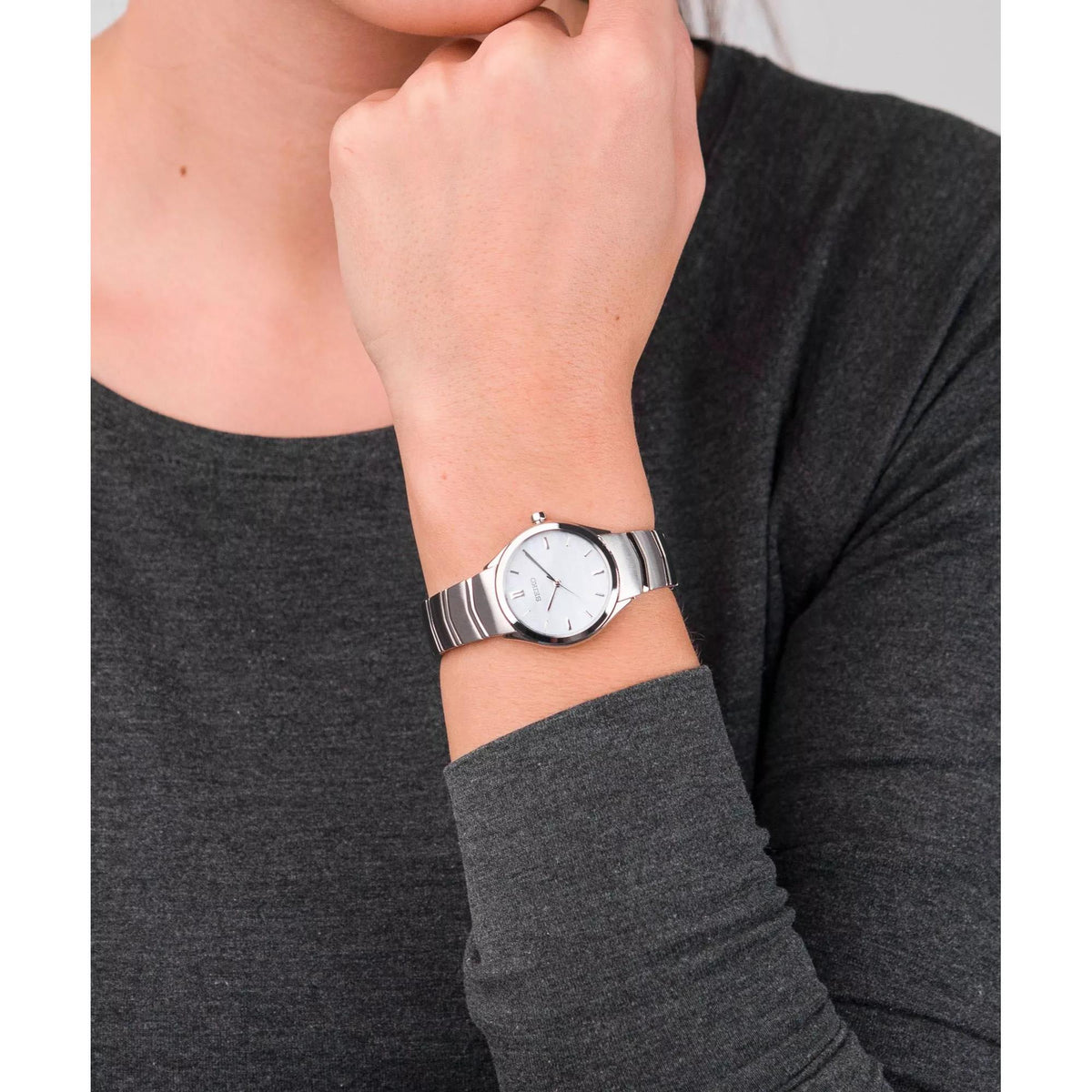 Stainless steel quartz watch on wrist with white dial and metal bracelet