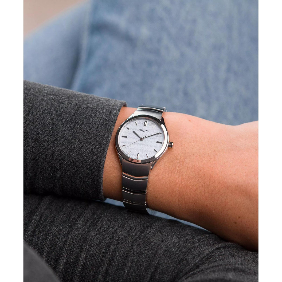 Stainless steel quartz watch on wrist with white dial and slim case