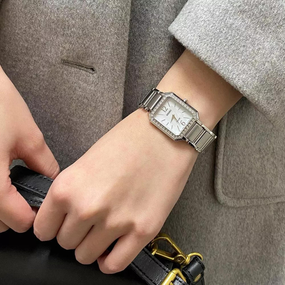 Seiko solar watch on wrist with mother-of-pearl dial and jeweled bezel, steel bracelet