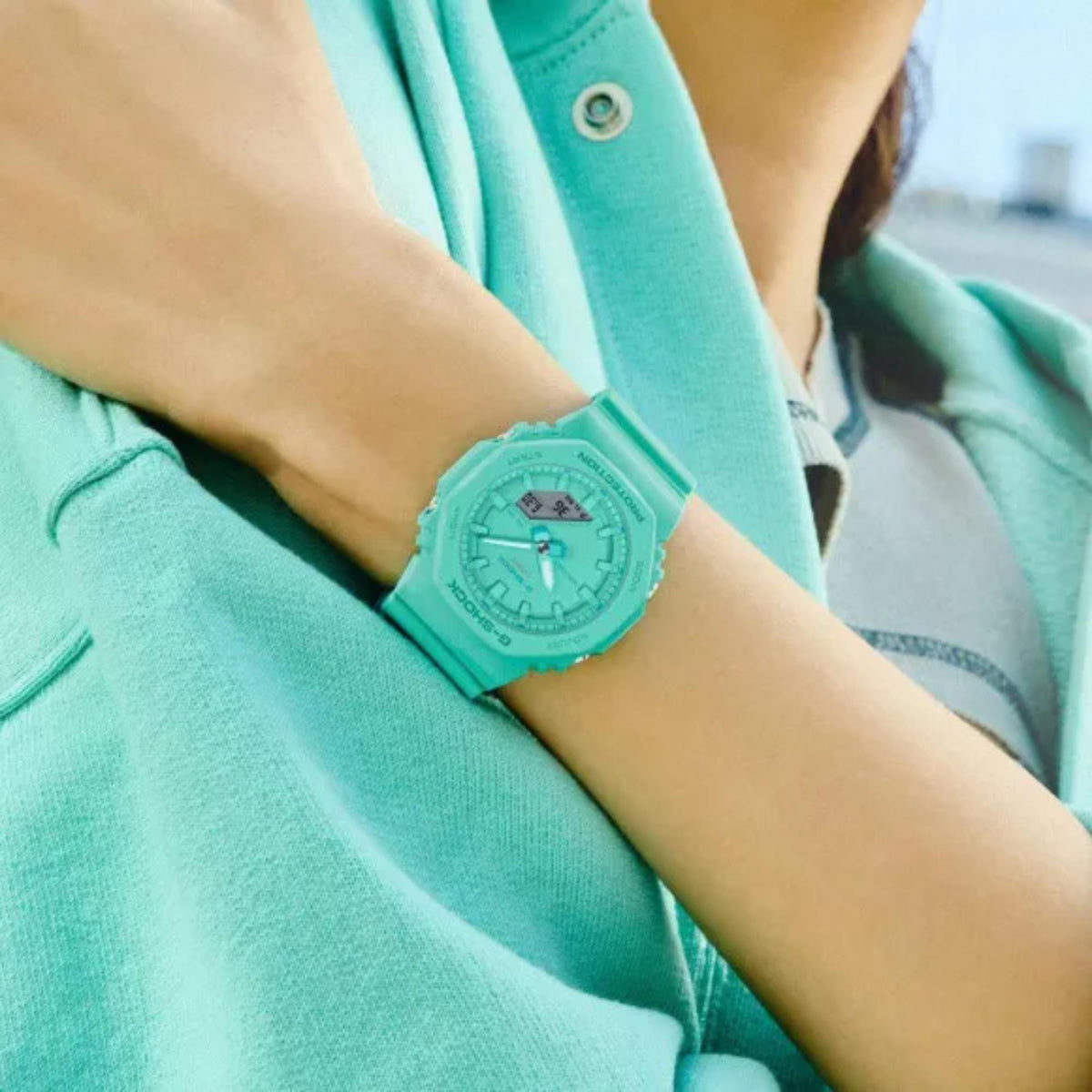 Turquoise resin watch on wrist with green dial, analog hands, and matching strap.