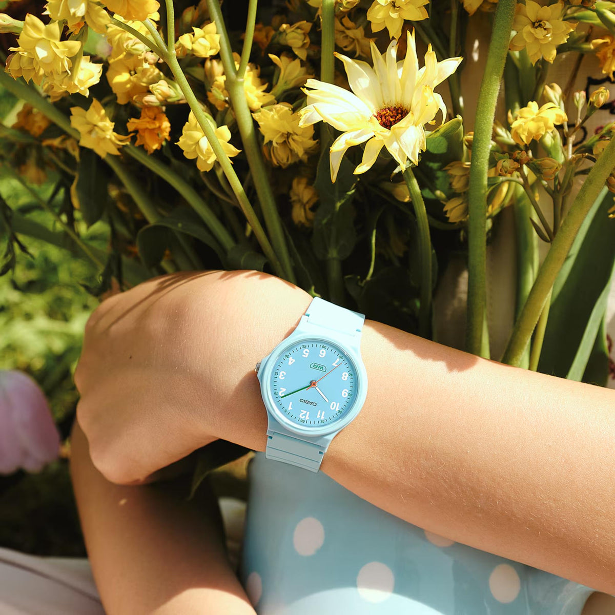 Light blue resin strap wristwatch on forearm with round blue dial
