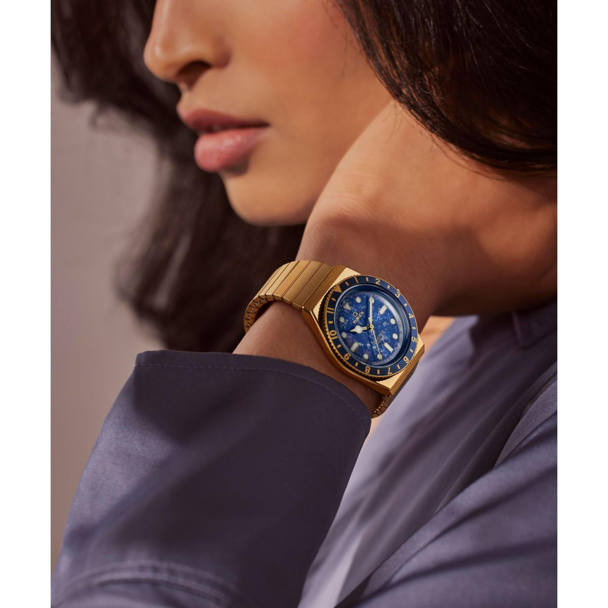 Blue dial quartz watch with gold-tone steel bracelet worn on wrist