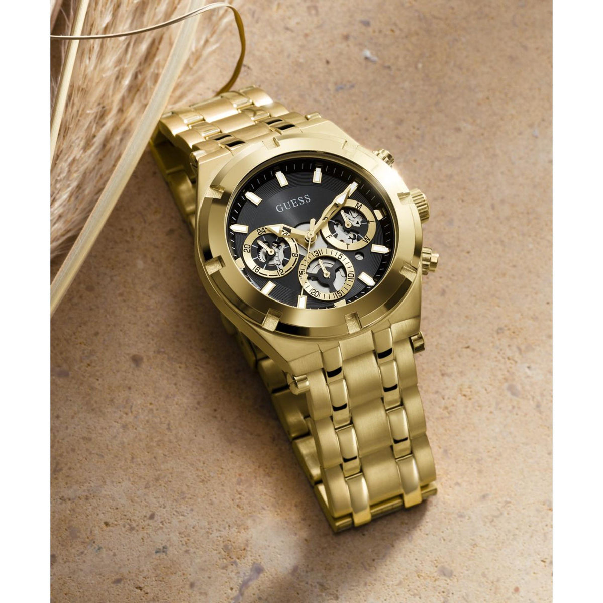 Men's gold-tone stainless watch on wrist with black dial and gold link bracelet
