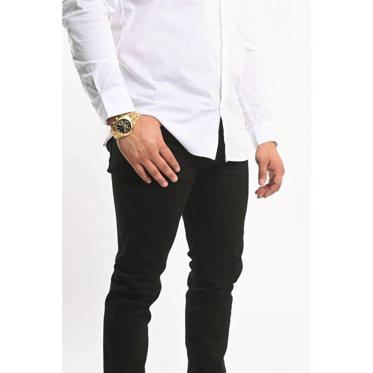 Men's gold-tone watch on wrist over black pants with black dial and gold bezel