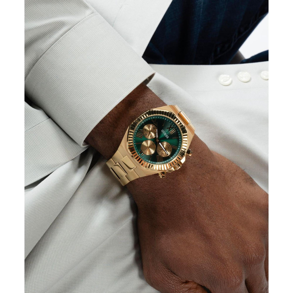 Gold-tone stainless steel watch on wrist with green dial and gold bezel accents