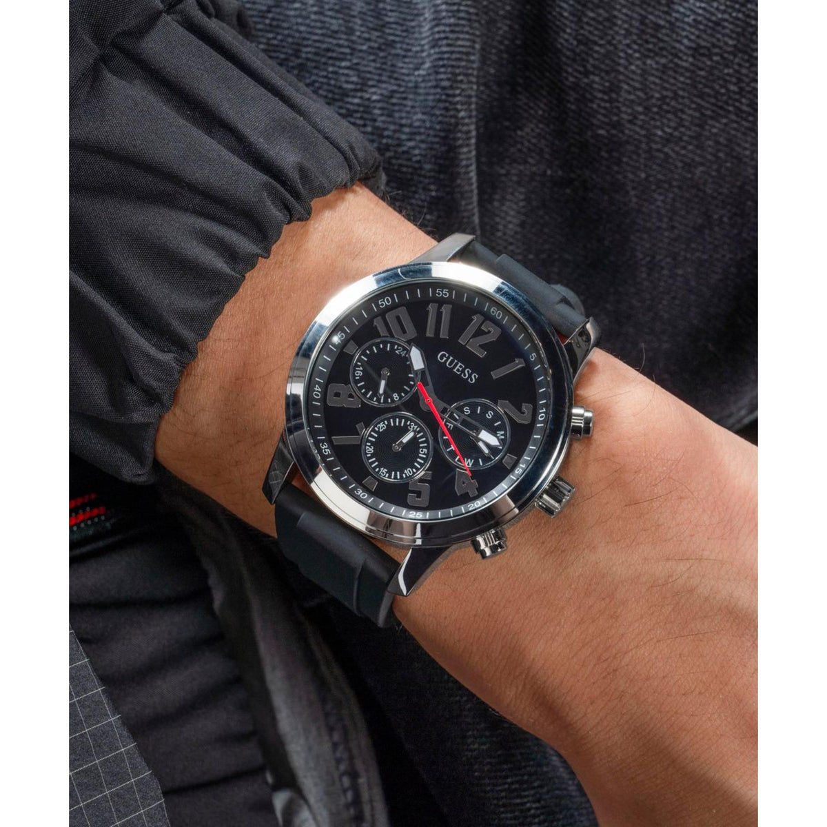 Men's chronograph watch on wrist with black dial, red accents, black silicone strap