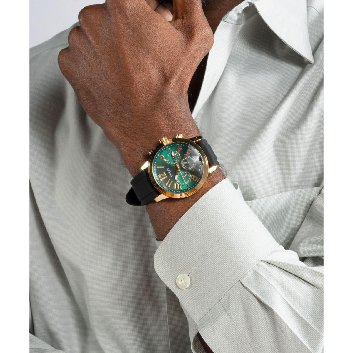 Men's watch on wrist with green dial and black silicone strap, gold-tone case