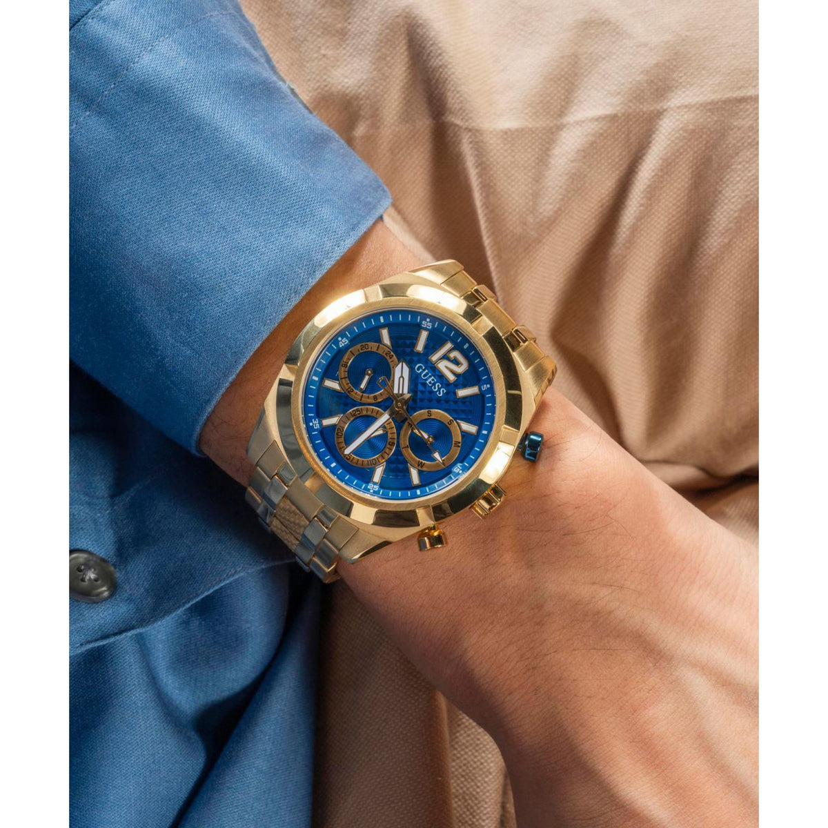 Gold-tone stainless steel watch with blue dial and three subdials on wrist