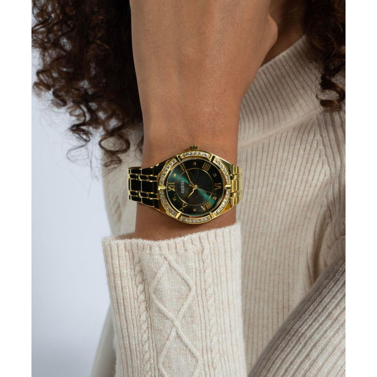 Women’s gold-tone watch with green dial, gold hands, and crystal bezel on wrist