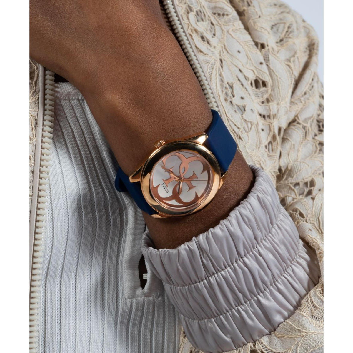 Women’s navy silicone watch on wrist, rose-gold bezel and white dial with GUESS logo