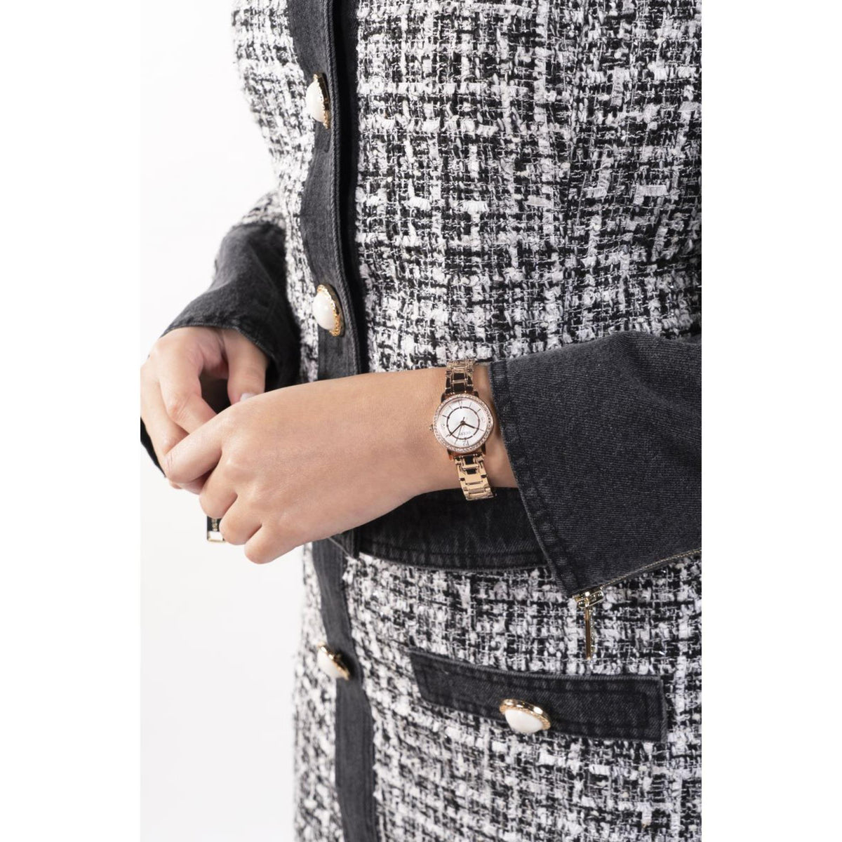 Woman wearing gold-tone wristwatch with white dial on textured tweed sleeve