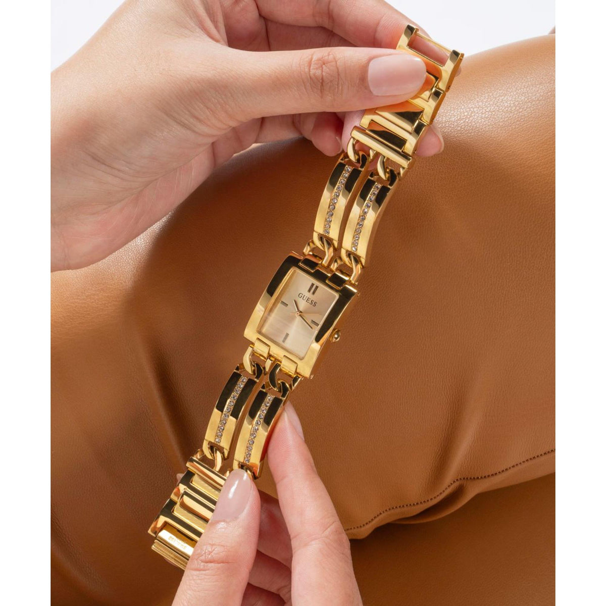 Gold-tone watch close-up on wrist with rectangular champagne dial and crystal insets