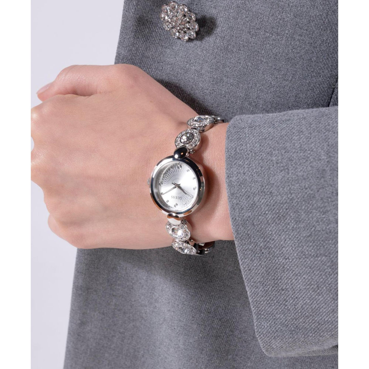 Women’s silver-tone round watch with gray dial and crystal-studded bracelet on wrist