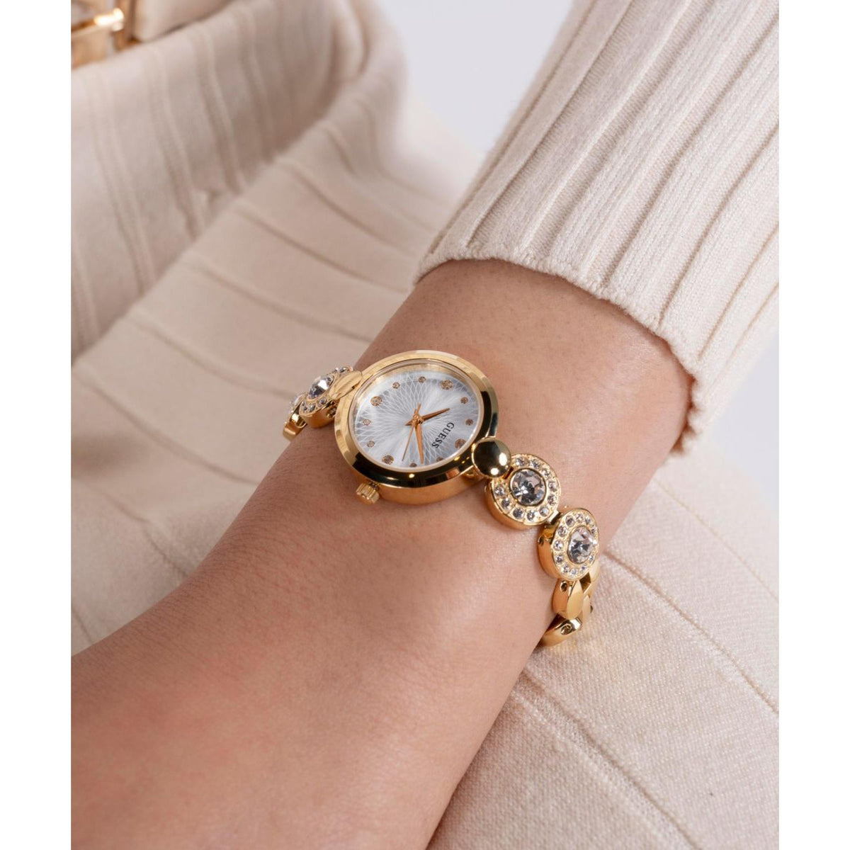 Women’s gold-tone watch worn with white dial and glittering crystal bracelet links