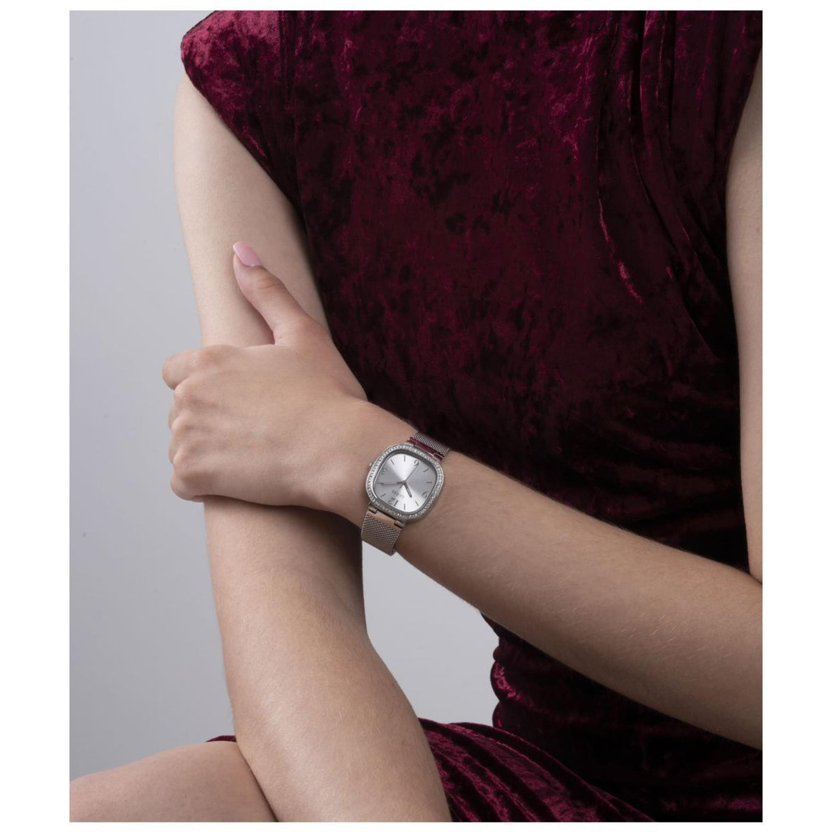 Women’s silver mesh strap watch with rounded square dial and crystal bezel on wrist