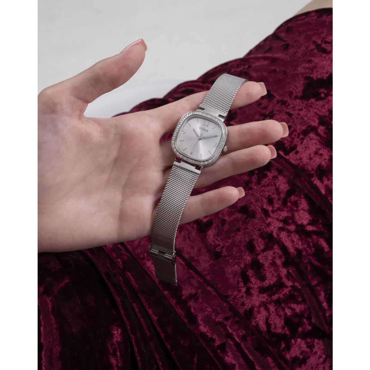 Women’s stainless steel mesh strap watch on open hand, rounded square silver dial