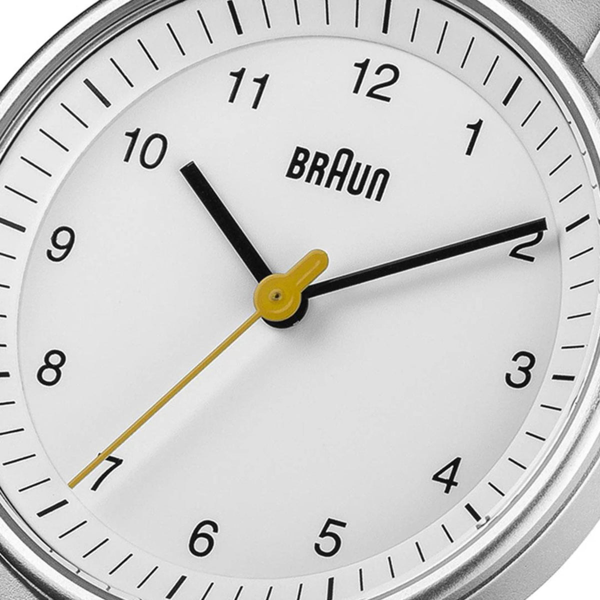Close-up white watch dial with Braun logo, black hour marks, and gold center hands